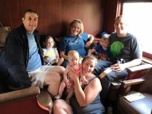 Photo of my family on a train 3 children, their mom and dad and 2 grand parents